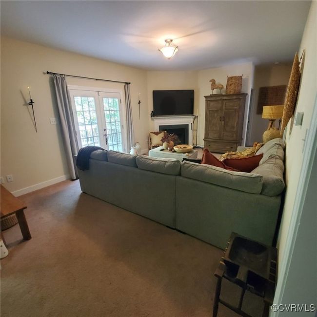 Carpeted living area with french doors, baseboards, and a fireplace | Image 18