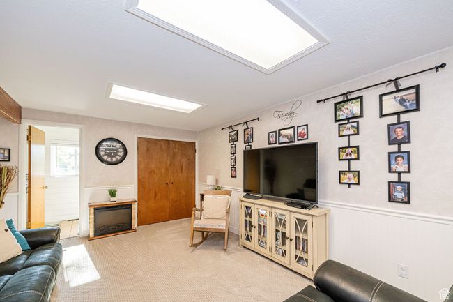Living area featuring carpet flooring, a wainscoted wall, and a fireplace | Image 24