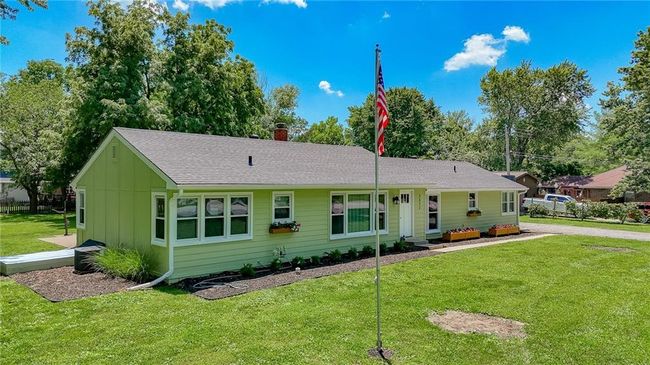 Ranch-style home featuring a front yard, a chimney, board and batten siding, and a shingled roof | Image 39