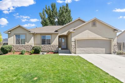 Ranch-style house featuring a garage and a front lawn | Image 1