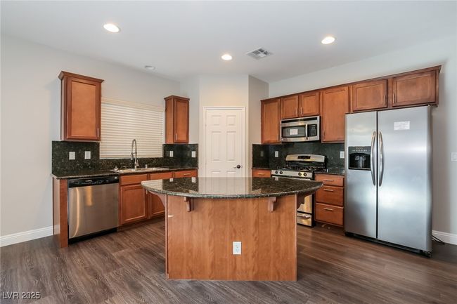 Kitchen featuring a sink, stainless steel appliances, a kitchen bar, visible vents, and a kitchen island | Image 6