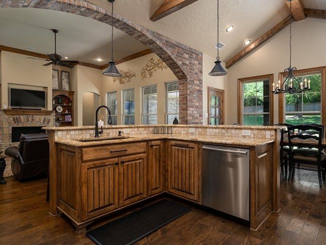Kitchen featuring a sink, arched walkways, open floor plan, ceiling fan with notable chandelier, and dishwasher | Image 10