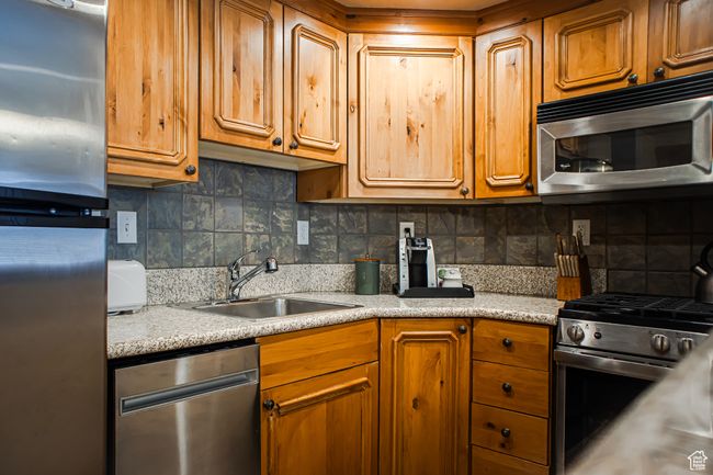 Kitchen with appliances with stainless steel finishes, brown cabinetry, a sink, and tasteful backsplash | Image 9
