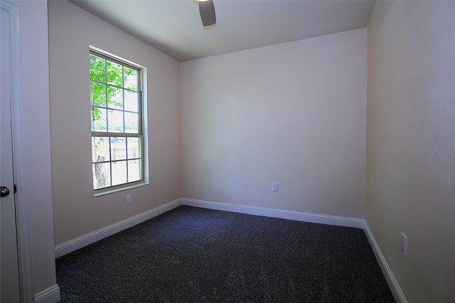 Unfurnished room featuring dark colored carpet, a ceiling fan, and baseboards | Image 7