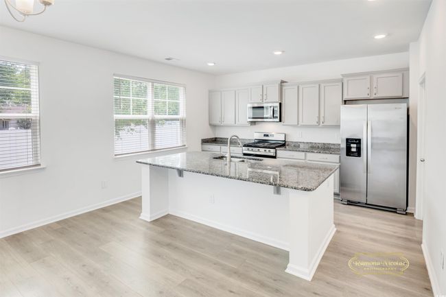Kitchen with appliances with stainless steel finishes, a sink, a center island with sink, light wood-type flooring, and recessed lighting | Image 10