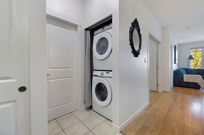 Clothes washing area with stacked washing maching and dryer, baseboards, light wood-style flooring, and laundry area | Image 25