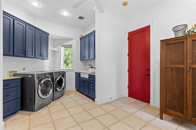 Washroom with separate washer and dryer, crown molding, cabinet space, and a sink | Image 26