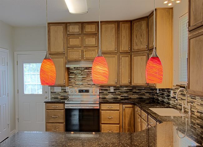 Kitchen with brown cabinetry, stainless steel range with electric stovetop, and a sink | Image 7