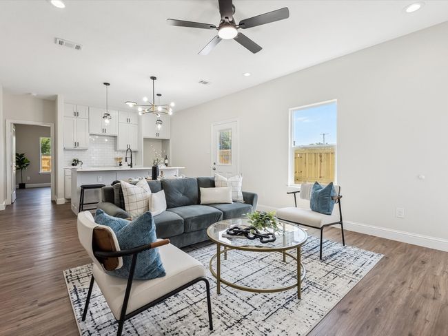 Living room featuring ceiling fan with notable chandelier, baseboards, dark wood-type flooring, and visible vents | Image 4