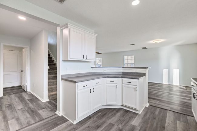Kitchen with a peninsula, Grey wood-style vinyl flooring, dark countertops, white cabinets, and recessed lighting | Image 11