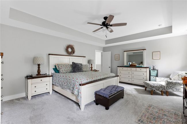 Bedroom featuring light colored carpet, a ceiling fan, baseboards, and a tray ceiling | Image 29