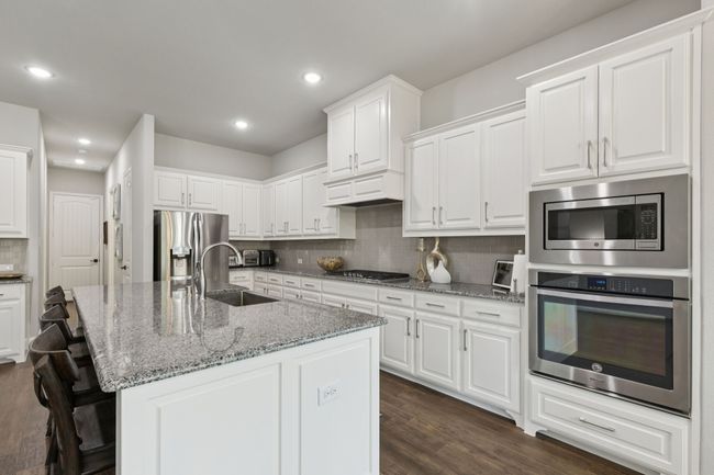Kitchen featuring stainless steel appliances, backsplash, white cabinets, dark wood-style floors, and recessed lighting | Image 11