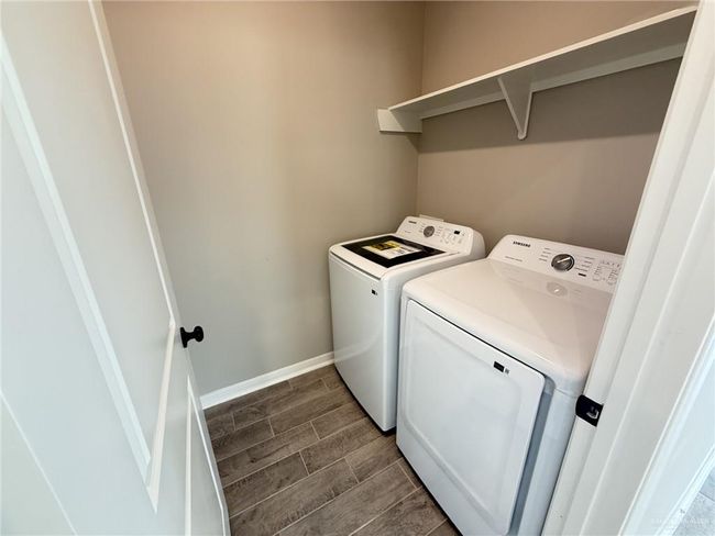 Clothes washing area featuring baseboards, laundry area, washing machine and clothes dryer, and wood finish floors | Image 10