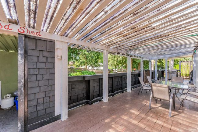 View of patio with a wooden deck, area for grilling, and outdoor dining area | Image 13