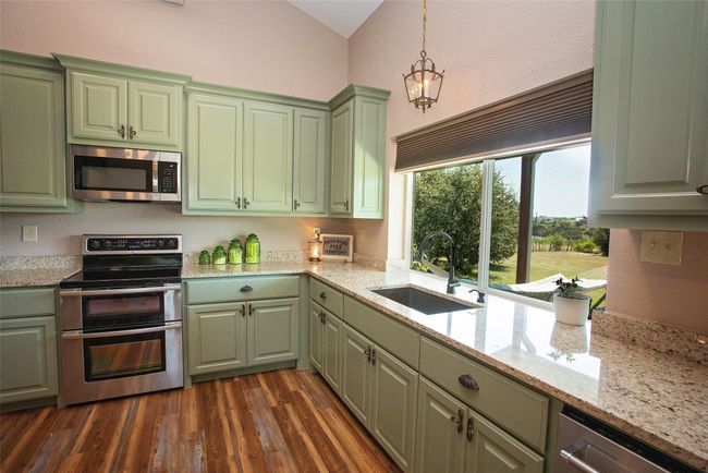 Kitchen featuring stainless steel appliances, green cabinets, vaulted ceiling, and dark wood-style flooring | Image 33