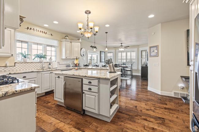 Kitchen with white cabinets, a center island, dark wood-type flooring, and a wealth of natural light | Image 31