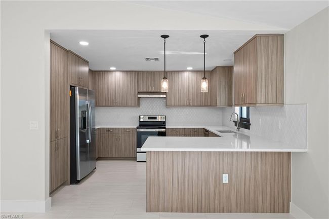 Kitchen featuring decorative light fixtures, stainless steel appliances, sink, kitchen peninsula, and backsplash | Image 11