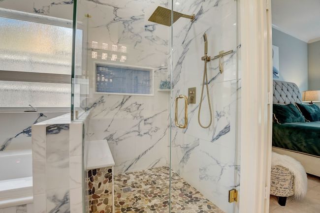 Primary en-suite features walk in shower with rainfall shower and porcelain tile | Image 15