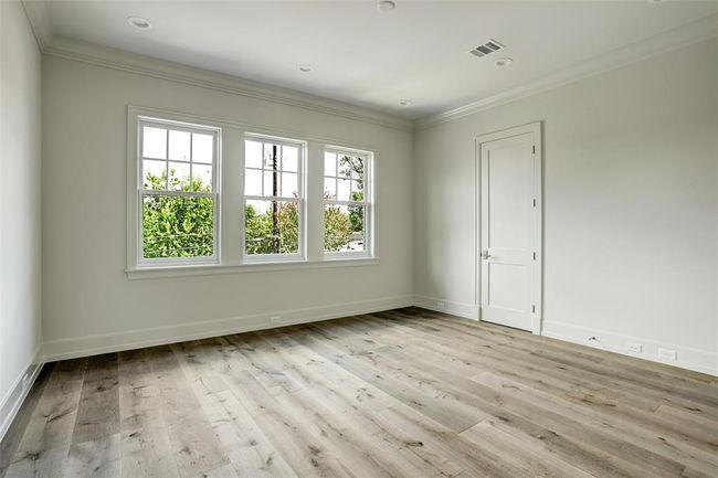 Bathed in natural light, this generously sized secondary bedroom is highlighted by a stunning wall of windows with serene views of the tree-lined street. Tall ceilings elevate the sense of space, creating a bright and graceful atmosphere. | Image 22