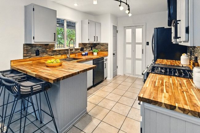 At the heart of the home is a stylishly renovated kitchen, where butcher block countertops meet contemporary cabinetry, a chic tile backsplash, and stainless steel Samsung appliances. | Image 8