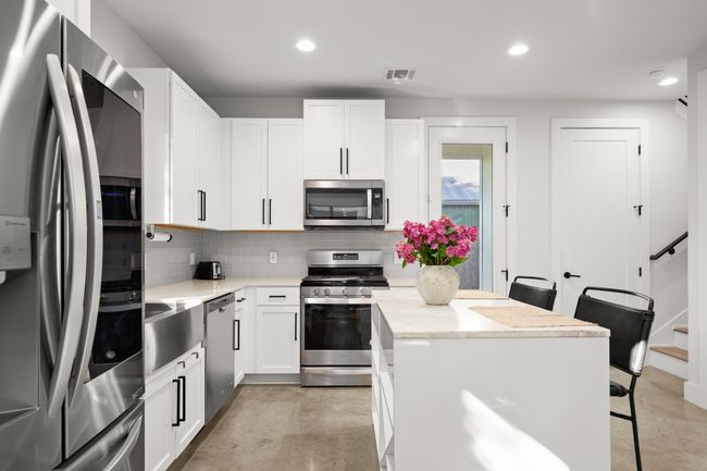 Kitchen with stainless steel appliances, tasteful backsplash, a breakfast bar, recessed lighting, and white cabinetry | Image 12