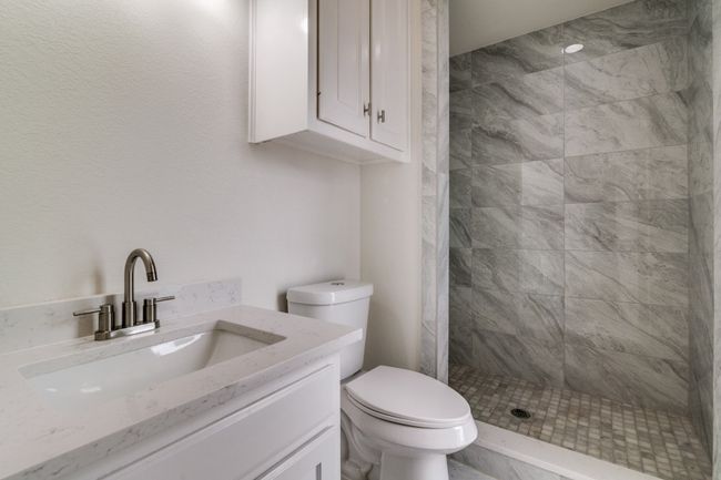 Bathroom featuring a tile shower, toilet, and vanity | Image 13
