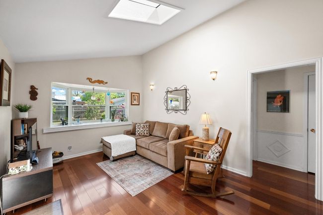 Living room featuring a skylight, wood finished floors, high vaulted ceiling, and baseboards | Image 6