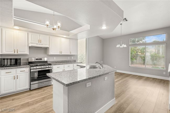 Kitchen with black microwave, stainless steel gas range, a sink, and an inviting chandelier | Image 8