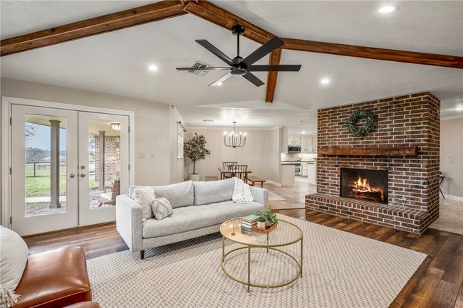 Living room with a brick fireplace, french doors, wood-type flooring, and lofted ceiling with beams | Image 11