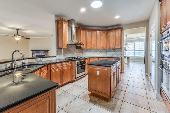 Kitchen with gas stovetop, oven, a sink, wall chimney range hood, and backsplash | Image 9