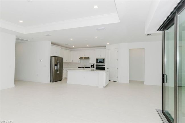 Kitchen with stainless steel fridge, built in microwave, black oven, under cabinet range hood, and light countertops | Image 27