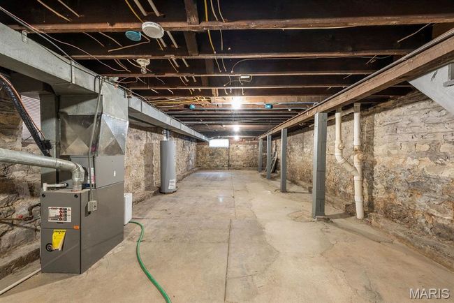 Unfinished below grade area featuring water heater and heating unit | Image 17