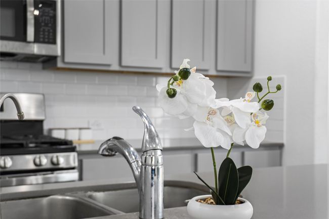 Details with stainless steel microwave, tasteful backsplash, and gray cabinets | Image 10