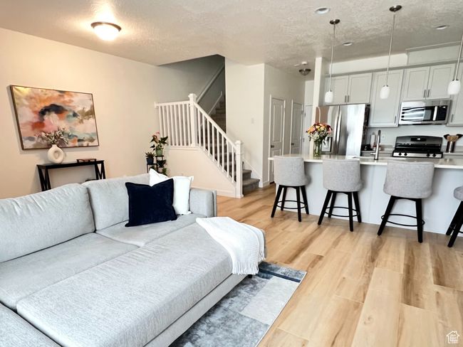 Living area featuring light wood-style flooring, stairs, and a textured ceiling | Image 7