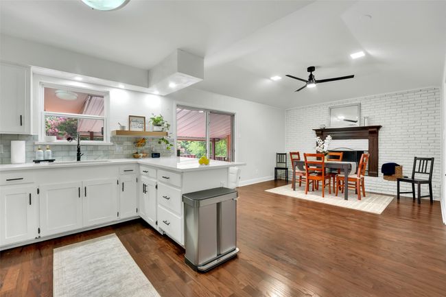 Kitchen with a ceiling fan, white cabinetry, brick wall, plenty of natural light, and light countertops | Image 27