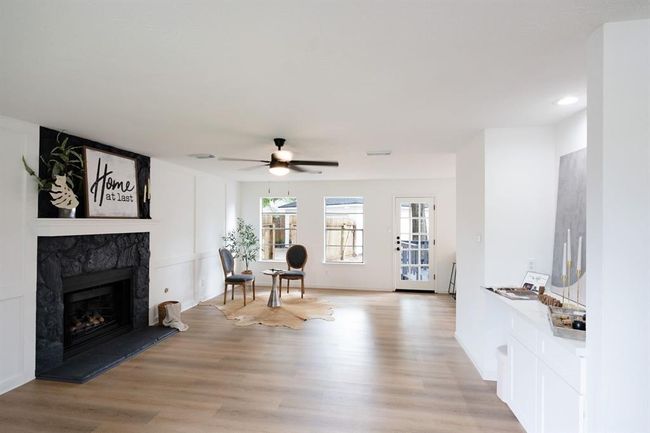 To the left, an inviting open concept area centered around a beautiful fireplace — ideal for family time or hosting guests. | Image 11