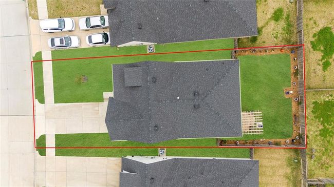 An aerial view of the entire house reveals the modern design, with the white exterior accented by black details, giving it a contemporary and elegant look. The spacious front porch, with the green front door, is a focal point, welcoming visitors. The driveway extends alongside the house, providing ample parking. Around the back, the pergola and stone patio are clearly visible. The overall layout of the home showcases its seamless integration with the outdoor spaces, providing a harmonious flow. | Image 31