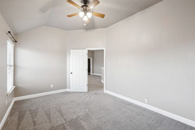 Carpeted spare room featuring plenty of natural light, lofted ceiling, and ceiling fan | Image 30