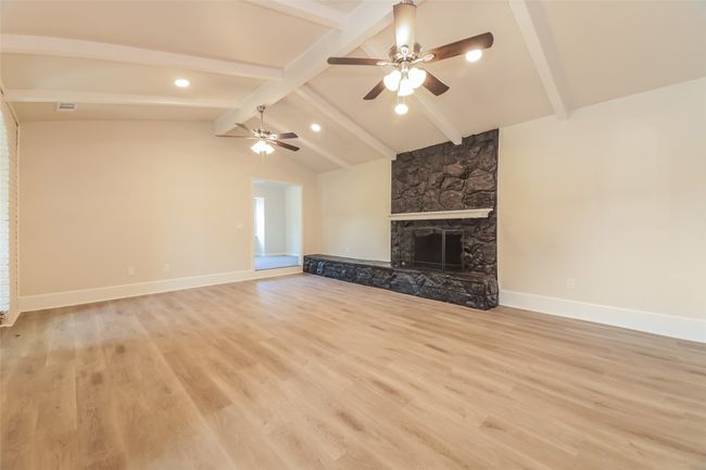 Unfurnished living room featuring a ceiling fan, light wood-type flooring, a fireplace, and recessed lighting | Image 4