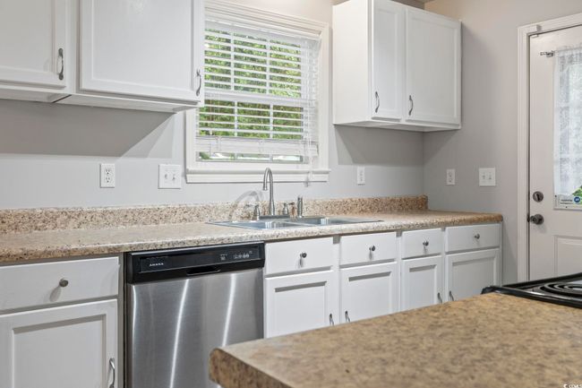Kitchen featuring stainless steel dishwasher, a sink, white cabinetry, and light countertops | Image 10