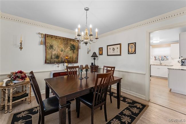 Dining space with crown molding, light wood-style flooring, baseboards, and a chandelier | Image 7