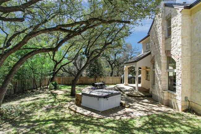 View of yard with a hot tub, a fenced backyard, ceiling fan, and a patio. | Image 37
