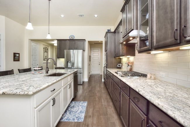 Kitchen with visible vents, a sink, dark brown cabinets, appliances with stainless steel finishes, and under cabinet range hood | Image 6