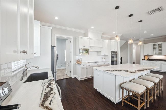 View of kitchen. The oversized island provides ample bar seating. Pantry/laundry room to back left. | Image 31