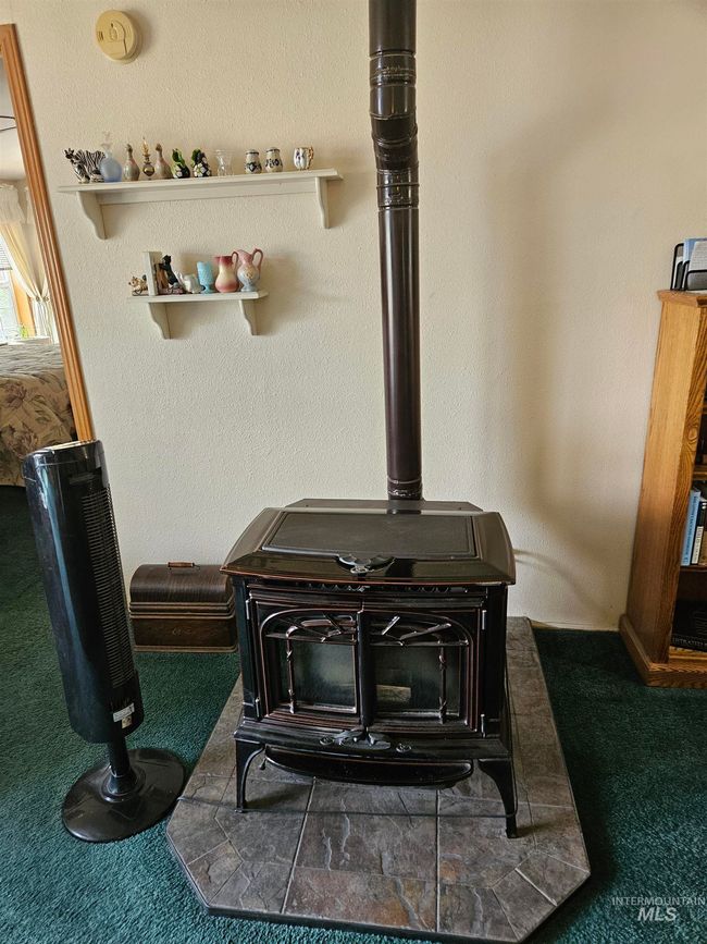 Detailed view of a wood stove, carpet, a textured wall, and a smoke detector | Image 8