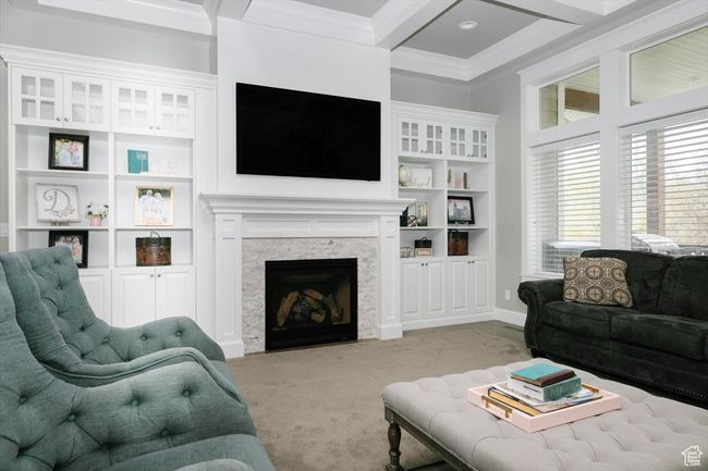 Living area with beamed ceiling, a stone fireplace, carpet floors, and crown molding | Image 27