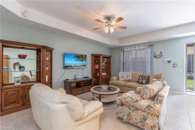 Living area with light tile patterned floors, ceiling fan, and baseboards | Image 8