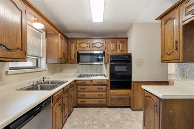 Kitchen featuring stainless steel appliances, a textured ceiling, and sink | Image 2