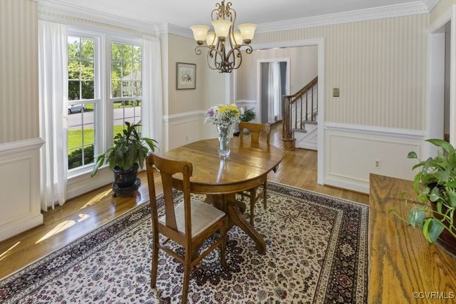 Dining room with wood finished floors, a chandelier, healthy amount of natural light, ornamental molding, and wallpapered walls | Image 19