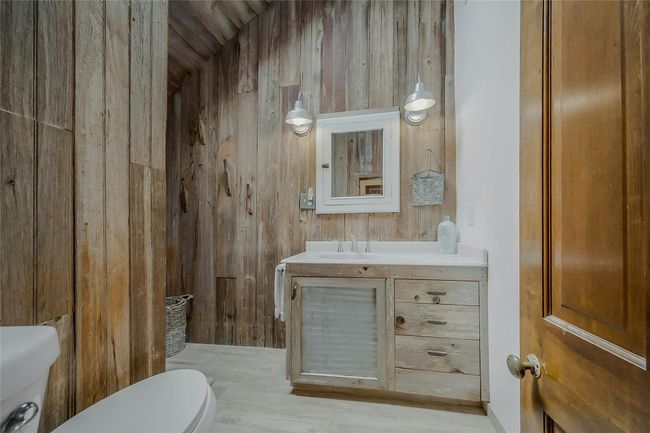 Full bath featuring toilet, wood walls, and vanity | Image 12